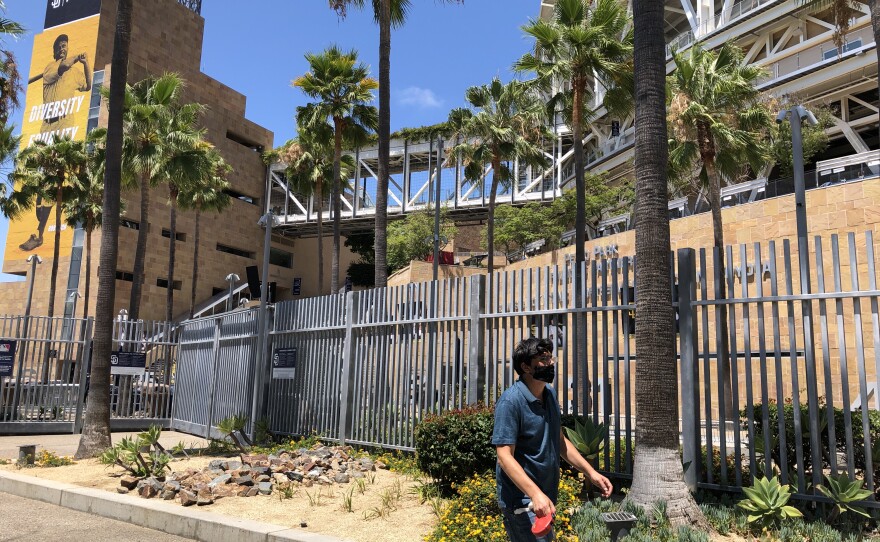 A pedestrian in a mask walks by Petco Park in Downtown San Diego. July 24, 2020.