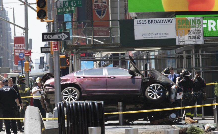 A car rests on a security barrier in New York's Times Square after it plowed through a crowd of pedestrians on Thursday.
