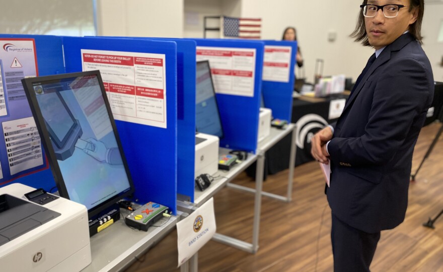 San Diego County Registrar of Voters Michael Vu stands next to a row of ballot marking devices at a satellite voting center in Spring Valley, Feb. 25, 2020.