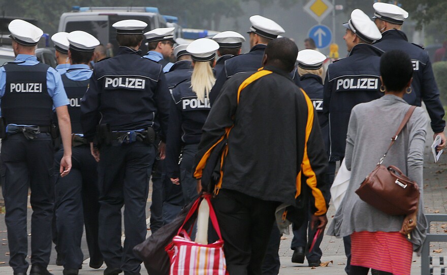 A couple leaves their apartment building and walks behind police during an evacuation of more than 60,000 people in Frankfurt on Sunday.