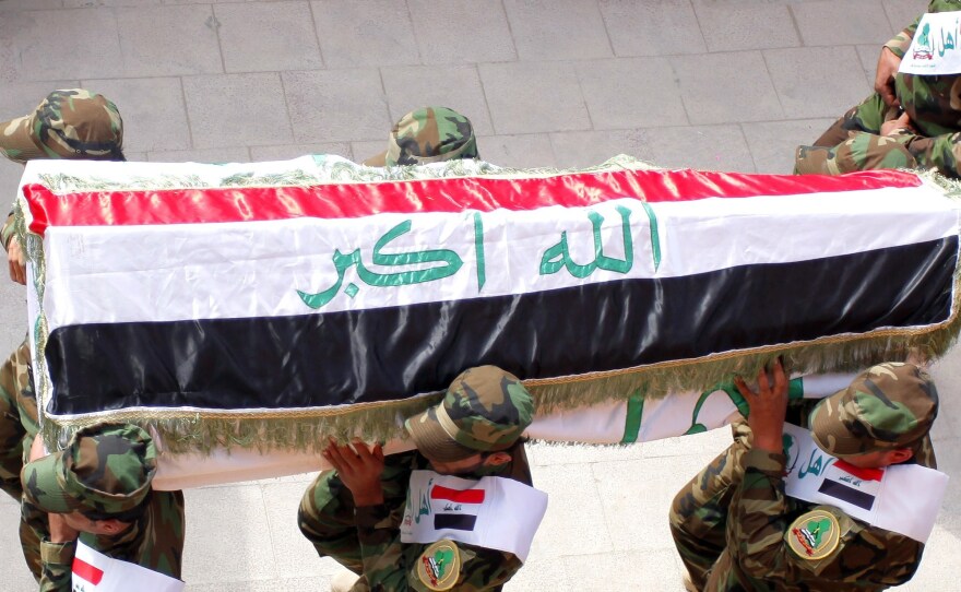 The coffin of an Iraqi fighter, who reportedly died fighting with the al-Haq militia alongside government forces, is carried prior to burial in Najaf this March. Najaf's clerics have called for more Shiites to take up arms.