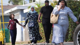 People hold hands near the scene of a shooting outside the Islamic Center of San Diego on Monday.