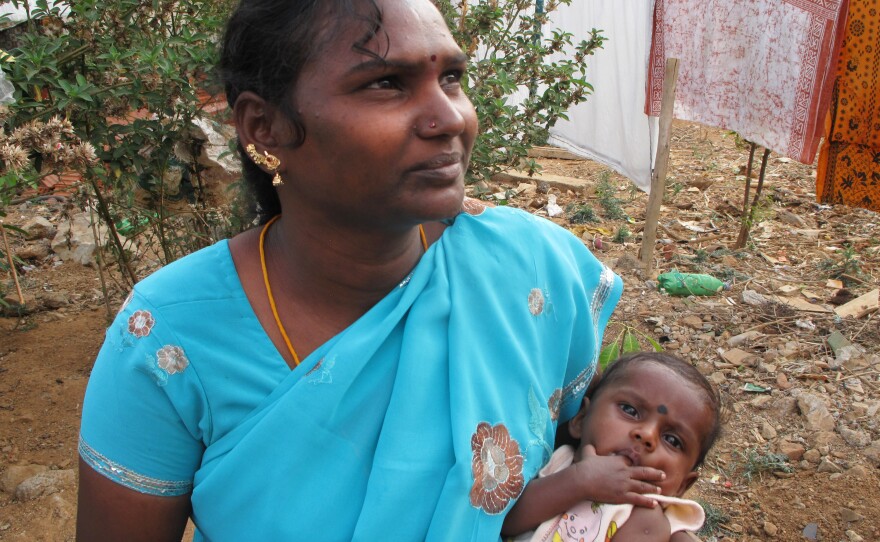 Anjali Subramaniam cradles her son, Aswin, who underwent open heart surgery free of charge. Subramaniam calls the doctors "a god" and the hospital a temple.