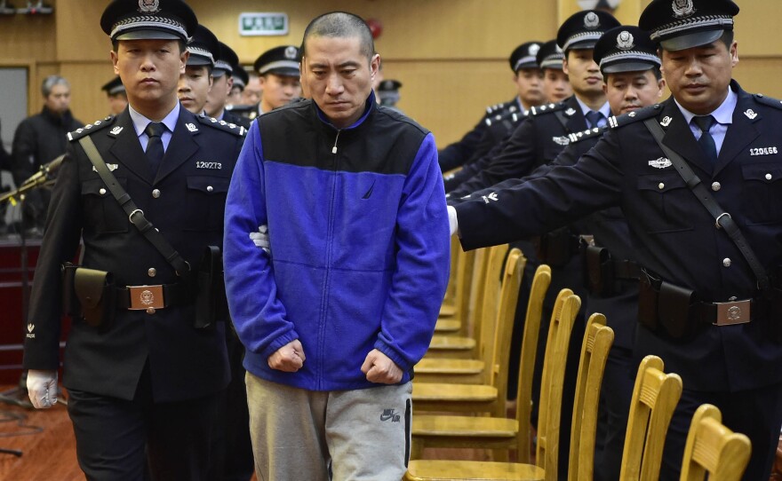 Ruihai International Logistics Chairman Yu Xuewei (center) is led by police officers as he arrives for his trial on Wednesday in north China's Tianjin Municipality.