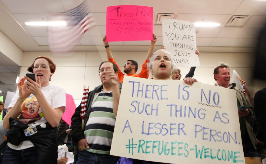 Protesters gather at Dallas-Fort Worth International Airport to denounce President Trump's executive order that bans certain immigration.
