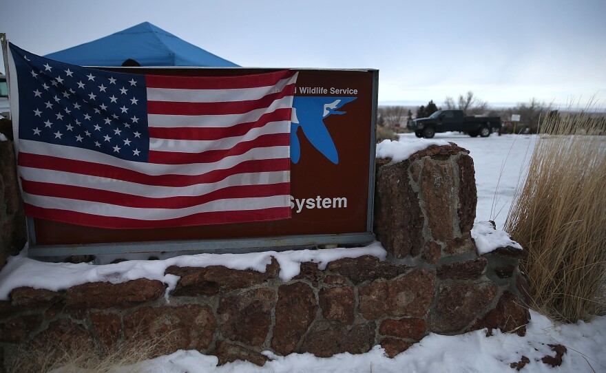 A U.S. flag hangs over a sign in front of the Malheur National Wildlife Refuge headquarters on Tuesday near Burns, Ore. An armed group has occupied the refuge since the weekend.