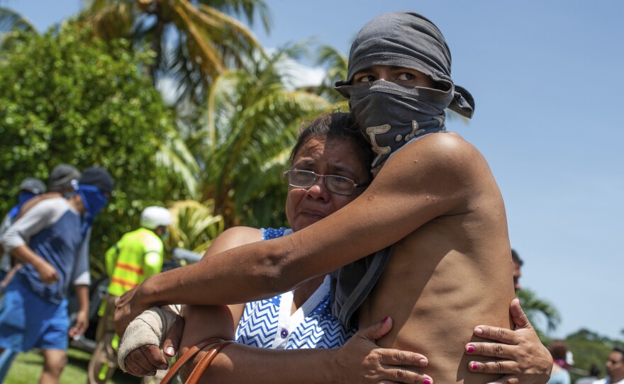 A student who had taken refuge at the Church of the Divine Mercy amid a barrage of armed attacks is embraced by a relative on Saturday after he was transported to the Managua Metropolitan Cathedral.
