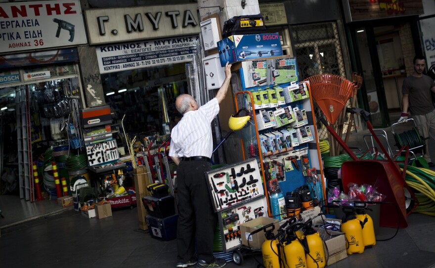 A shop owner arranges his goods in central Athens on Monday. Greek banks have reopened but capital controls remain in place.