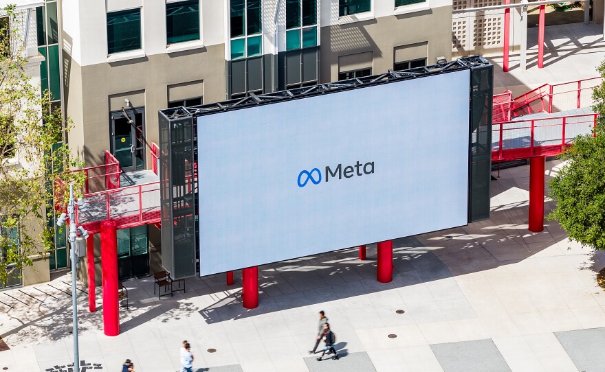 Workers walk past a display at Meta headquarters on Thursday, March 26, 2026, in Menlo Park, Calif.