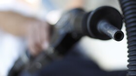 A San Diego gas station worker poses holding a gas nozzle, March 9, 2011.