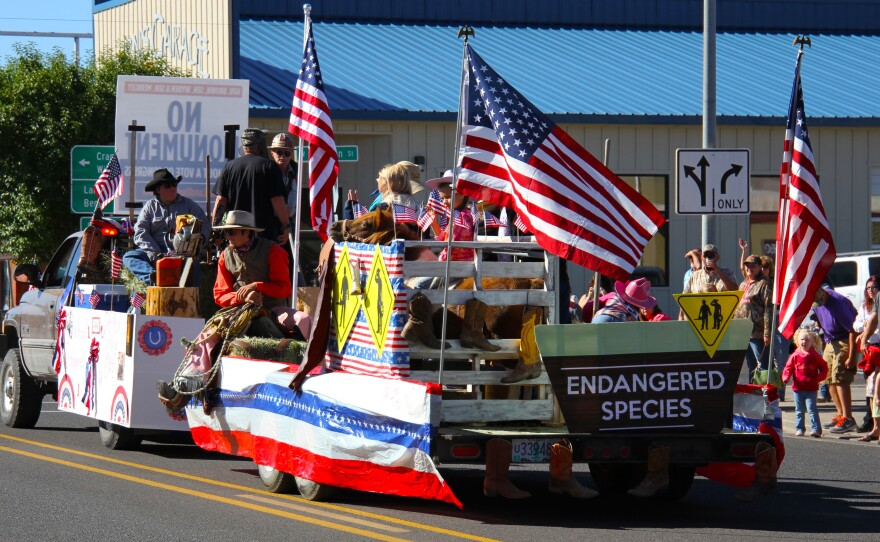 A float with costume-clad ranchers, loggers and miners passes through the center of Burns, Ore., during the annual Harney County Fair parade.