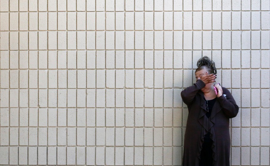 A woman wipes her tears at a community center where family members gathered to pick up survivors.