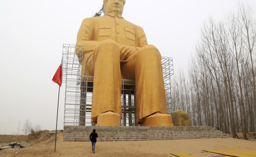 A man looks at the giant statue of Mao.