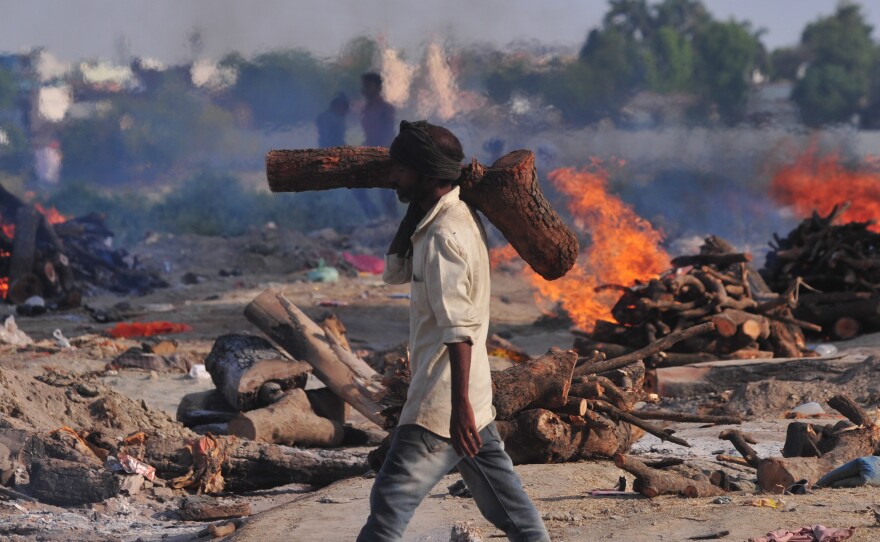 A worker carries wood to a mass cremation site on the banks of the Ganges River in Allahabad on Tuesday.