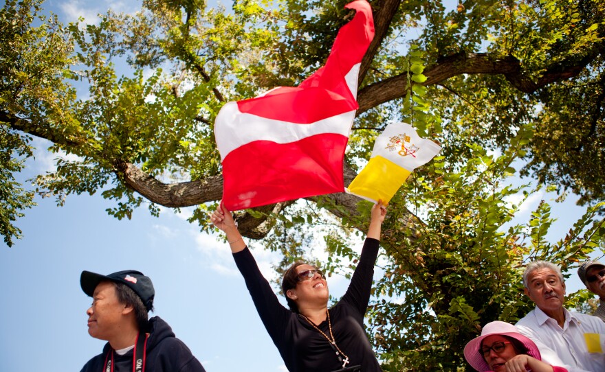 Patricia Briceno raises the Peruvian and Vatican flags on Constitution Avenue. "Peru is with him, and we love him," said Briceno, who is Peruvian.