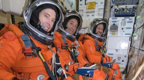 Seated on the mid-deck are astronauts Andrew J. Feustel (foreground), Michael J. Massimino and John M. Grunsfeld, all STS-125 mission specialists. "NOVA scienceNOW" covers the repair mission for the Hubble space telescope.