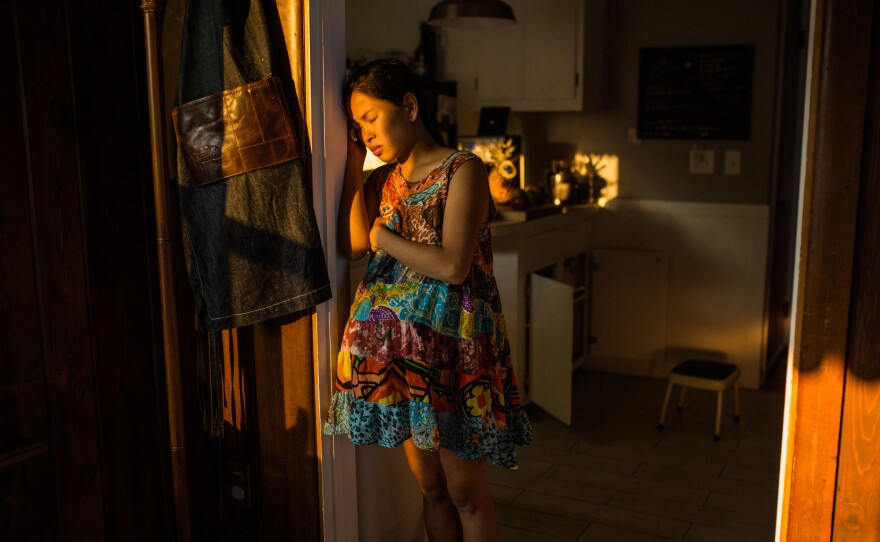 Cham Junglas, 29, rests her head against the door as she works through her labor pains for the home birth of her second child, Theodore. Junglas felt that the hospital experience of her first labor removed her from the intimate experience of birthing her child.
