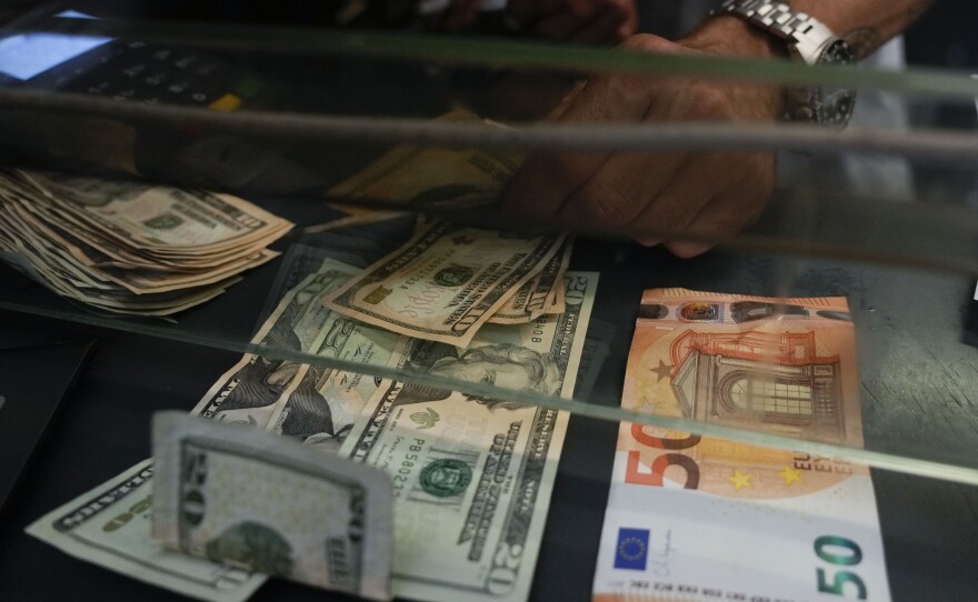 A cashier changes a 50 Euro banknote with US dollars at an exchange counter in Rome, Wednesday, July 13, 2022.