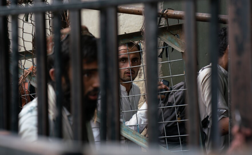 People wait on the Afghan side at the Torkham border crossing, either to leave the country or to greet returnees.