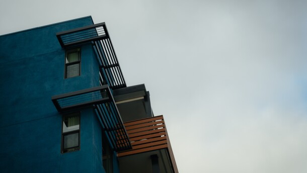 The corner of a blue-painted building with a brown balcony.