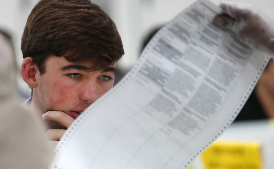 A Republican observer looks at a ballot during a hand recount last November in Broward County, Fla. Florida officials and lawmakers are still learning about cyberattacks there.