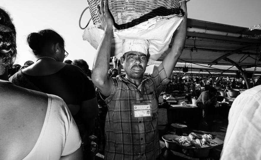 A basket man carries a load of fish through Kasimedu Fishing Harbour in Chennai, India. Nearly 1,000 of the roughly 5,000 workers carry fish this way. They're mostly migrant laborers who earn about $5 a day.