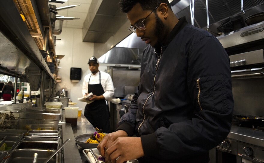 Onwuachi cooks in the kitchen of his D.C. restaurant, Kith and Kin. His food encompasses a range of African, Caribbean, African-American and other influences.