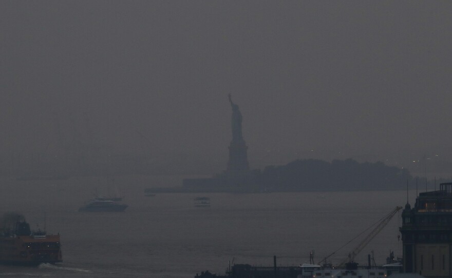 The Staten Island Ferry departs from the Manhattan terminal through a haze of smoke from Western wildfires, with the Statue of Liberty barely visible on July 20.