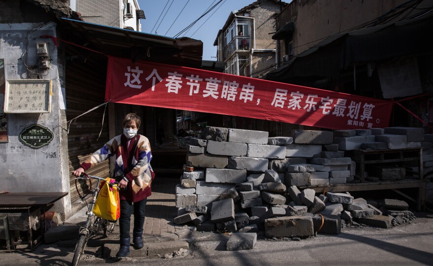 Housing compounds in Wuhan are closing off many entrances to restrict movement. The banner says that even during the spring festival, staying at home is the best deal.