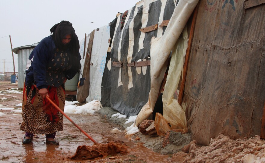 A Syrian refugee shovels mud in front of a makeshift shelter in an unofficial camp for Syrian refugees in Iaat in Lebanon's Bekaa Valley on Tuesday.