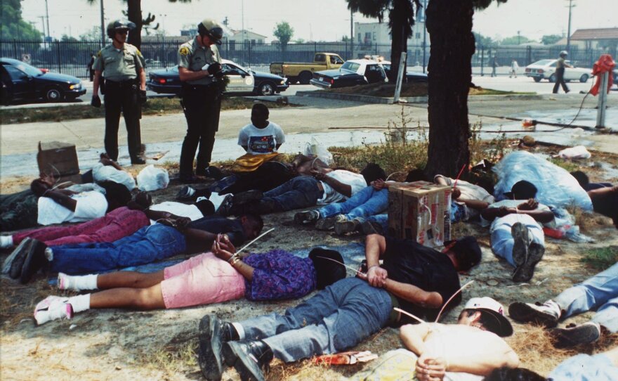 Police stand over a group of handcuffed looting suspects in Los Angeles on April 30, 1992, as rioting continued throughout the area.