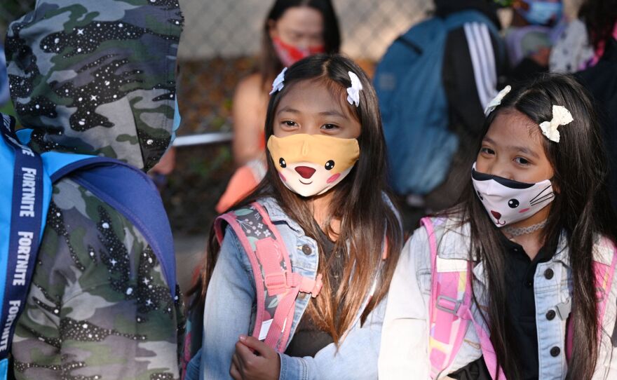 Students and parents arrive masked for the first day of the school year at Grant Elementary School in Los Angeles on Aug. 16. The reopening of schools has raised hope some parents may return to the labor force.