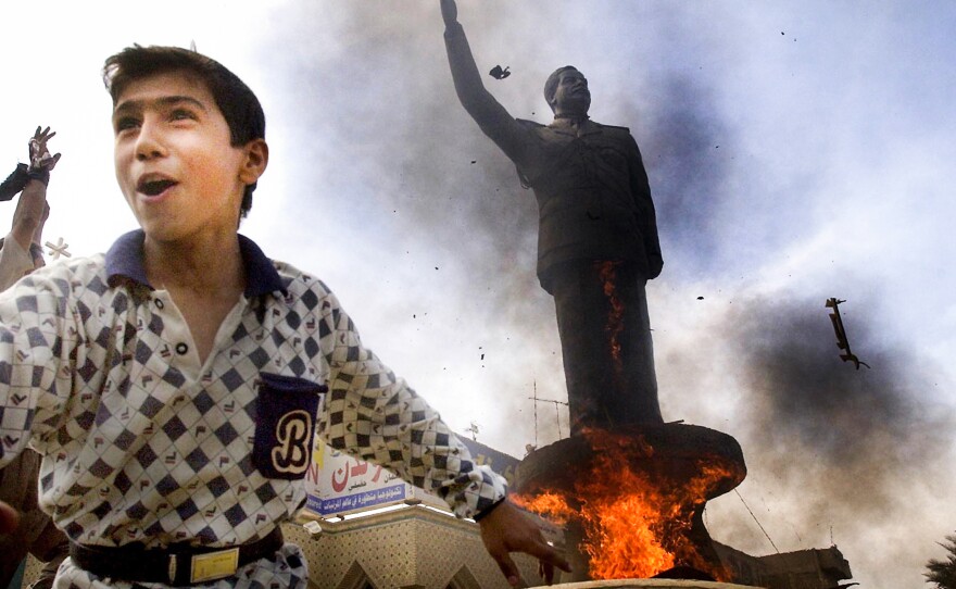 An Iraqi boy cheers as a statue of ousted Iraqi President Saddam Hussein is set ablaze during an impromptu celebration on the streets of Baghdad on April 12, 2003.