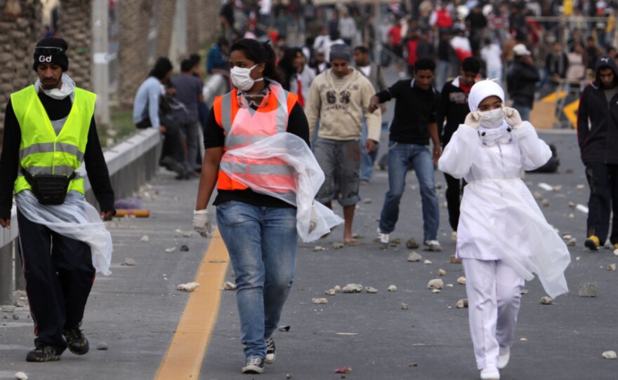 A Bahraini nurse (right) walks with anti-government protesters heading onto the streets of Manama to await a Saudi-led military force that crossed into Bahrain on Monday.
