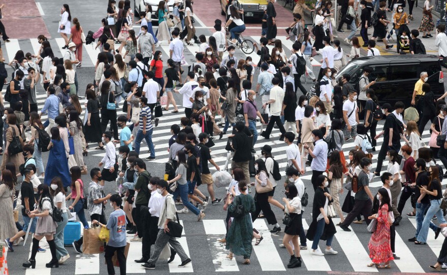 Pedestrians cross the landmark Shibuya Crossing intersection in the shopping and entertainment district of Shibuya in Tokyo on June 27, 2021.