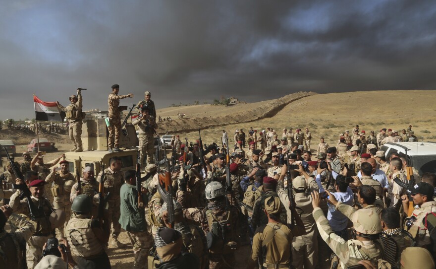 Iraqi army soldiers raise their weapons Thursday in celebration on the outskirts of Mosul, Iraq.