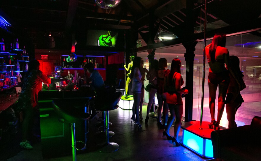 Working in the bars of the red-light district pays more than many office jobs or other service work that the women and men in Thailand's sex industry would otherwise qualify for. Above: Women dance at a bar in the Patpong red-light district in Bangkok.