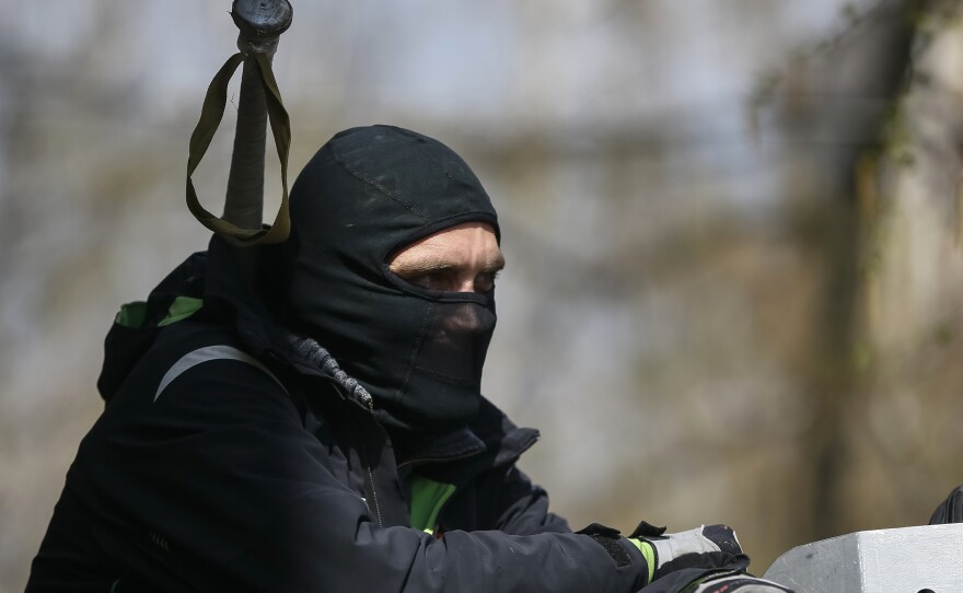 One of the pro-Russia protesters who have taken over the police headquarters in Slovyansk, Ukraine, watched from the barricades on Tuesday. Ukrainian authorities said special forces were beginning an operation against the demonstrators.