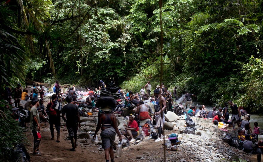 Migrants rest alongside the Acandiseco river after climbing up muddy trails.