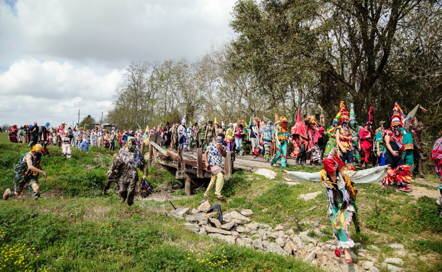 Mardi Gras revelers walk to the next house for another round of the chicken chase.