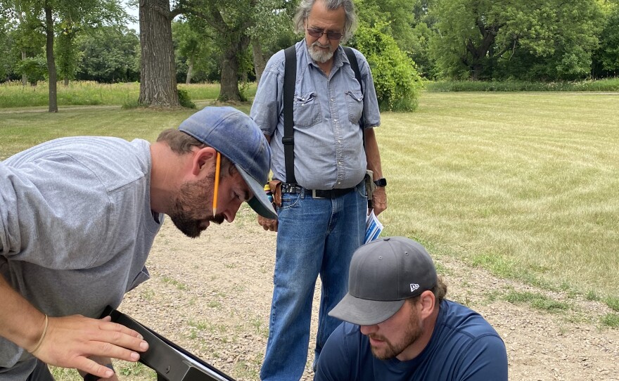 John Robertson watches as workers install new signs on property that is now managed by tribal members.