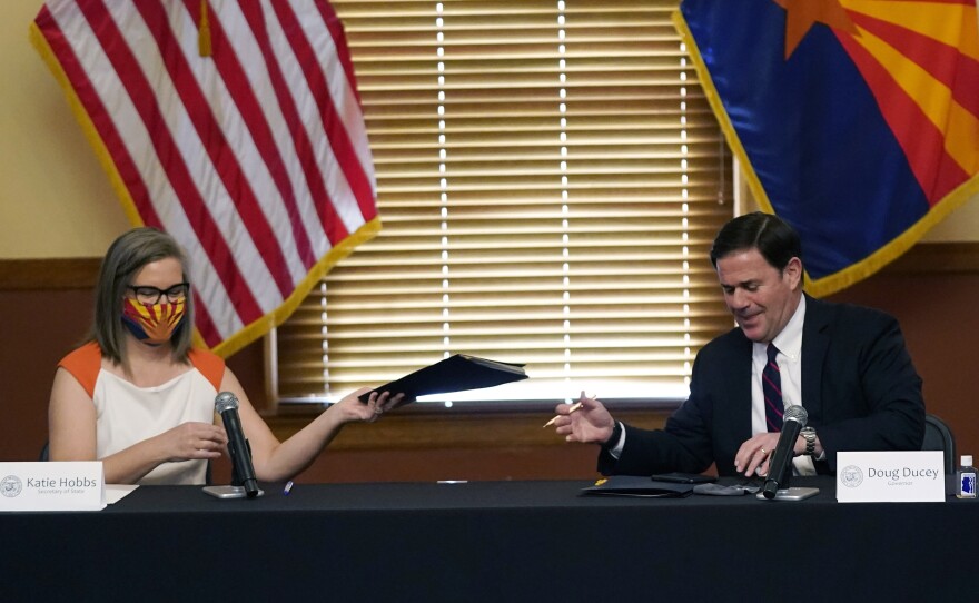 Arizona Secretary of State Katie Hobbs and Gov. Doug Ducey exchange election documents as they certify election results Monday at the Arizona Capitol in Phoenix.