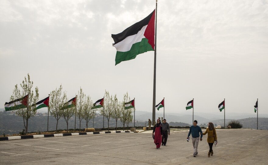 Palestinians exit the Rawabi showroom after viewing the development. On the ridge behind the Palestinian flag is the Israeli settlement of Ateret. The flag, billed as the biggest Palestinian banner, has been stolen three times, Rawabi employees say — and they blame Israeli settlers.