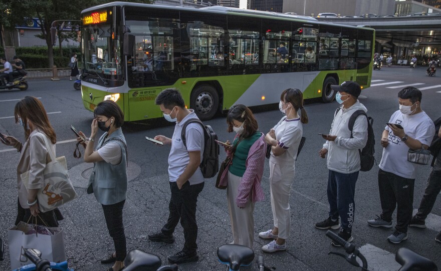 Commuters wait in line for public buses as they leave work in the business district on Aug. 27 in Beijing. China's Supreme People's Court has ruled that it's illegal for companies to subject employees to the practice known as "996," or working 9 a.m. to 9 p.m. six days a week.