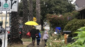 A mother walks her children home from school as a brief thunder storm settles over Sherman Heights in San Diego, Jan. 31, 2019.