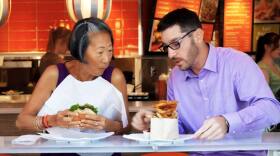 Host Su-Mei Yu eats a burger with Robert Lane in front of Burger Lounge. Lane is the Vice President, Marketing at Burger Lounge Restaurants.