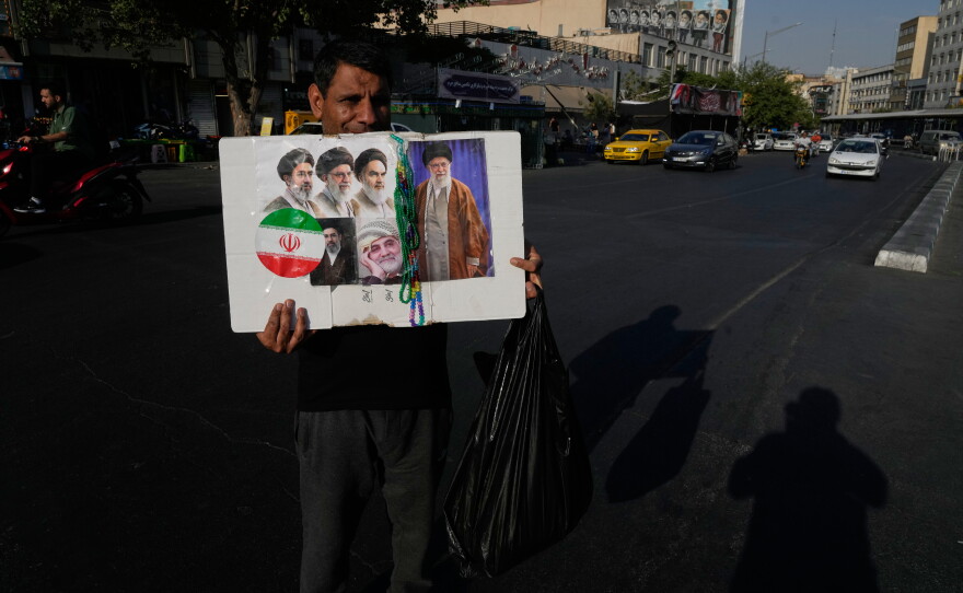 A man displays a placard with portraits of the current and late supreme leaders and the late Revolutionary Guard Gen. Qassem Soleimani at the Islamic Revolution Square in downtown Tehran, Iran, Saturday, July 18, 2026.
