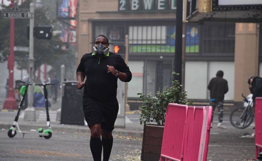 A Portland, Ore., resident wears a respirator to protect himself from wildfire smoke as he jogs in downtown in September 2020.