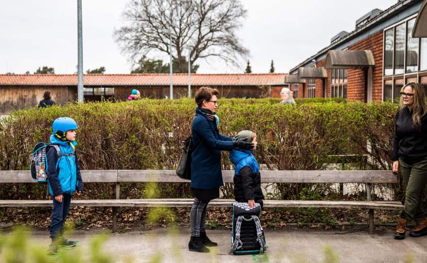 Parents and their children stand in line waiting to get inside Stengaard School north of Copenhagen, Denmark.