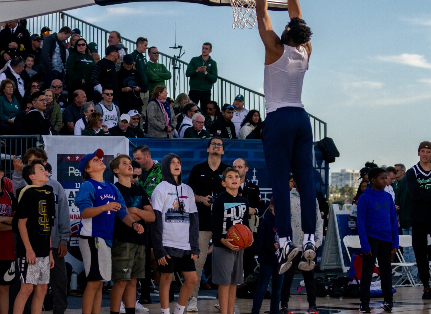 Young fans watch as a player slam dunks the ball aboard the USS Abraham Lincoln on Nov. 11, 2022.